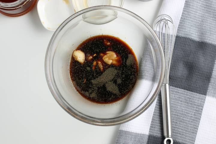 Balsamic vinegar, olive oil, mustard, and honey in a bowl to make balsamic salad dressing.