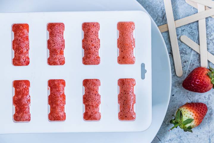 Strawberry puree poured into popsicle molds.