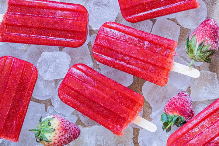 Strawberry popsicles on a bed of ice.