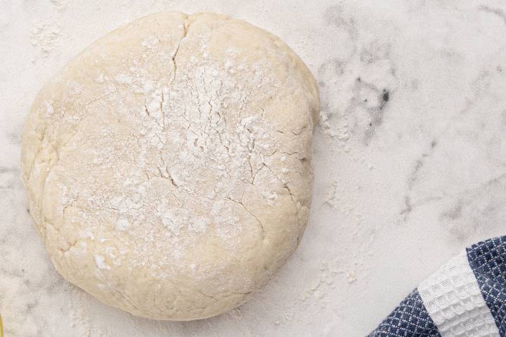 Greek yogurt pizza dough rolled on a marble surface.