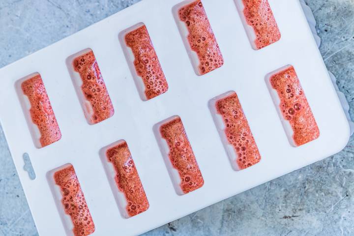 Watermelon puree poured into popsicle molds.