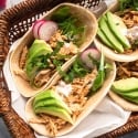 Healthy slow cooker chicken barbacoa tacos with avocado, cilantro, and radishes in corn tortillas.
