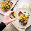 Whole30 grilled chicken with mango salsa and fresh limes on a plate.