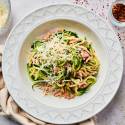 Garlic parmesan zucchini noodles with ground sausage and red pepper flakes in a white bowl.