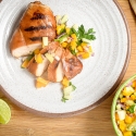 Grilled chicken with peach and cucumber salsa sliced on a plate.