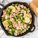 Lemon pepper shrimp and broccoli in a cast iron skillet with garlic, shrimp, and brocoli florets.