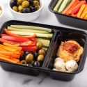 Mediterranean snack box with olives, carrots, hummus, cucumbers, tomatoes, and mozzarella cheese balls.