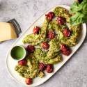 Juicy pesto chicken tenders topped with roasted cherry tomatoes and Parmesan cheese, served with extra pesto sauce on the side.
