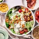 Protein packed salad bowls with chicken, bacon, chickpeas, cucumbers, quinoa, cherry tomatoes, green onions, and cottage cheese dressing.