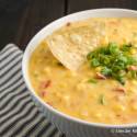 Jalapeno corn dip with cheddar cheese, tomatoes, jalapeno, onion, and corn in a bowl.