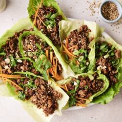 A top-down shot of a plate of Korean beef lettuce wraps and a side of shredded carrots.