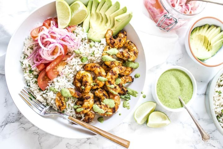 Peruvian shrimp rice bowls with grilled shrimp, white rice, cilantro mint sauce, salsa criolla, and sliced avocado.