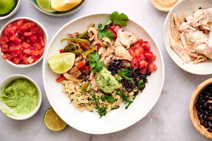 Rotisserie chicken taco bowl with black beans, bell peppers, onions, guacamole, and tomatoes.