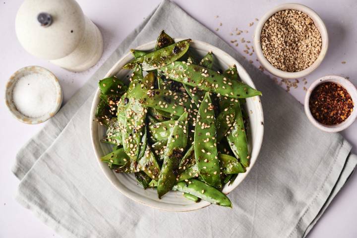 A  finished bowl of sesame sugar snap peas, garnished with sesame seeds.