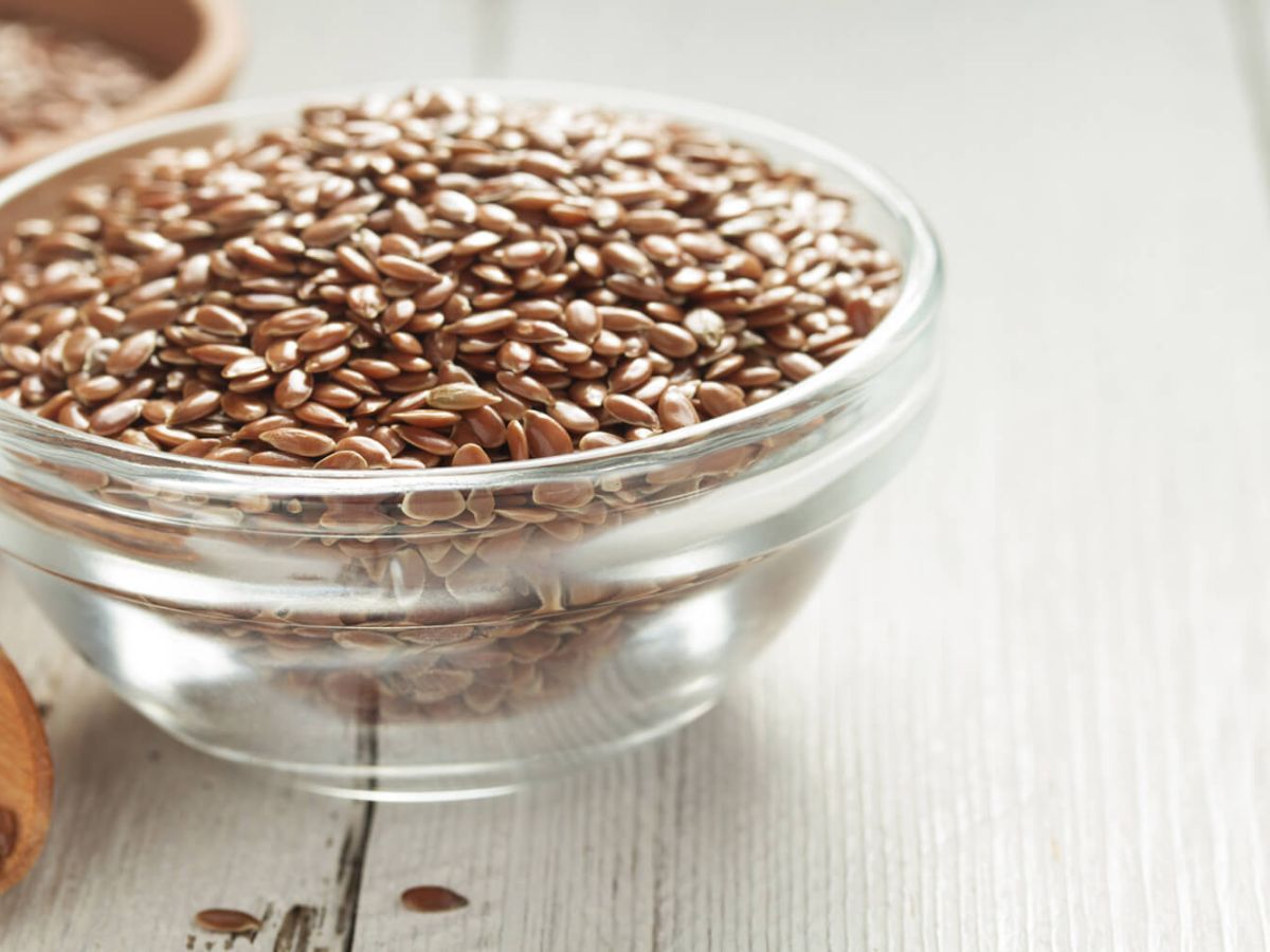 Bowl with flax seeds on a white surface