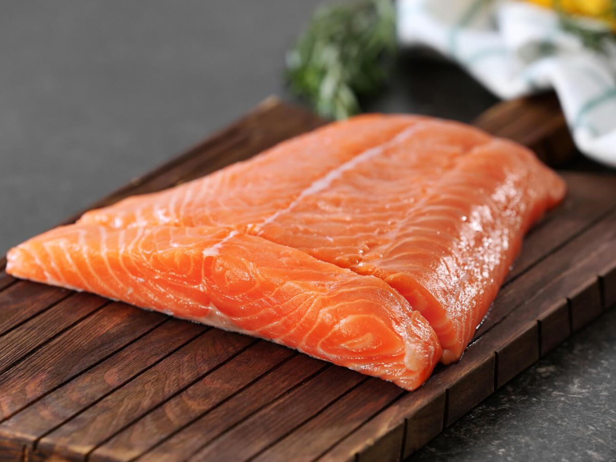 Salmon meat on brown chopping board