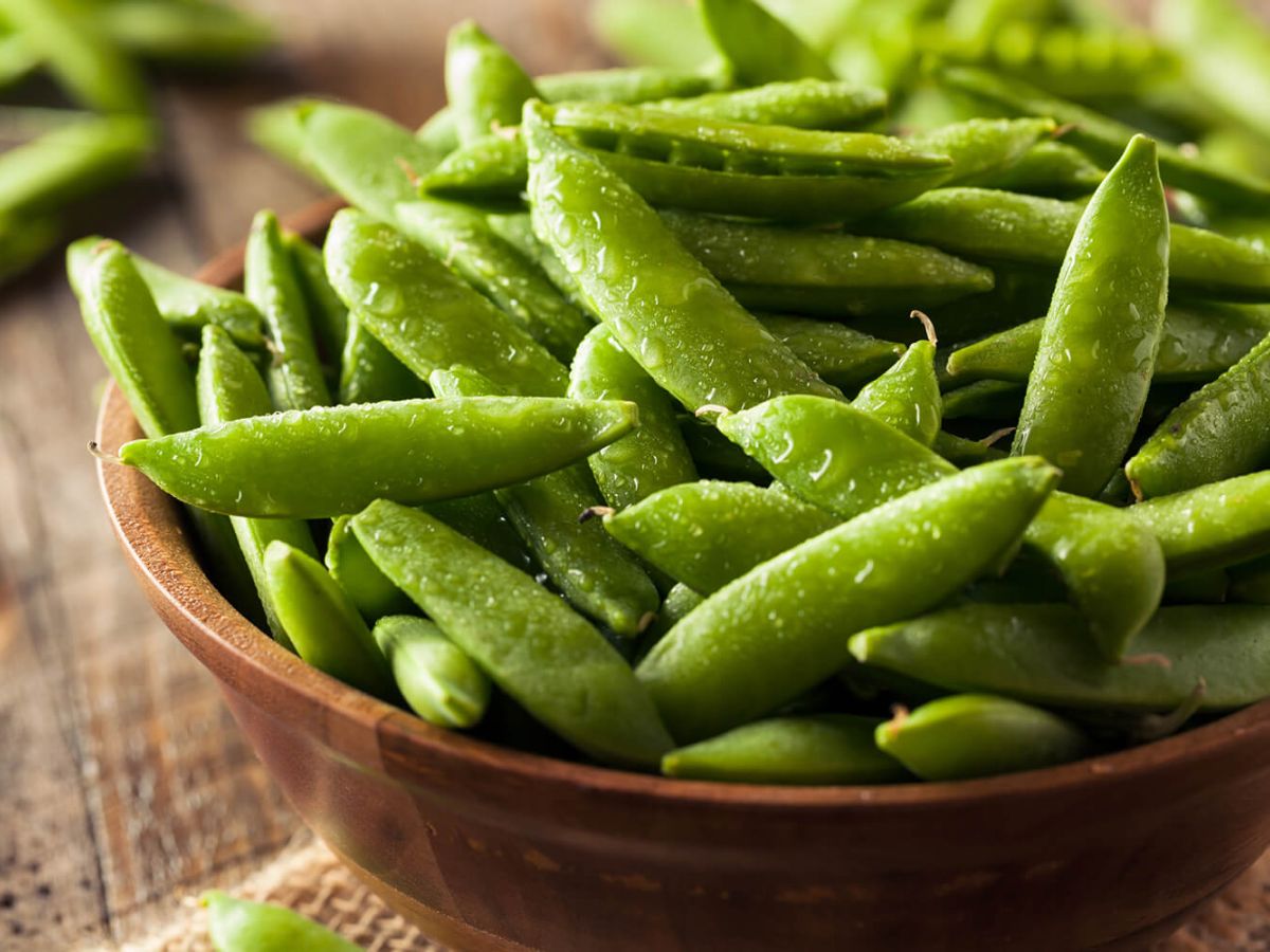 Fresh sugar snap peas on a wooden bowl