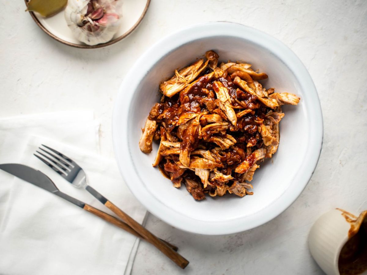 Slow cooker sweet and spicy chicken with soy sauce, Asian chili paste, and ginger in a bowl.